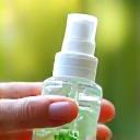 Hand holding a spray bottle with a green leaf icon indicating eco-friendly cleaning products.